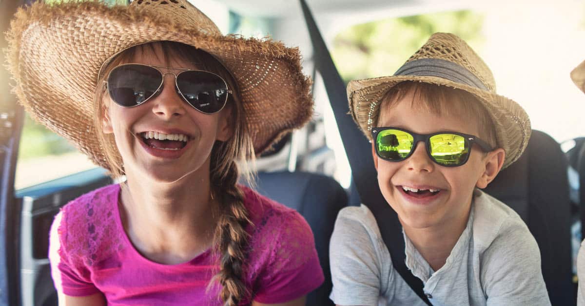 Two smiling children in a car.